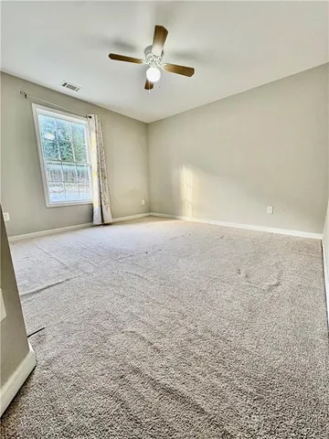 an empty room with windows and fan