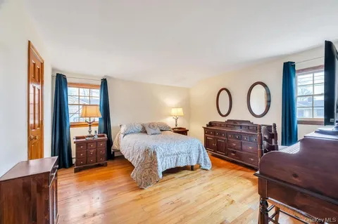 a bedroom with a bed a dresser next to a window
