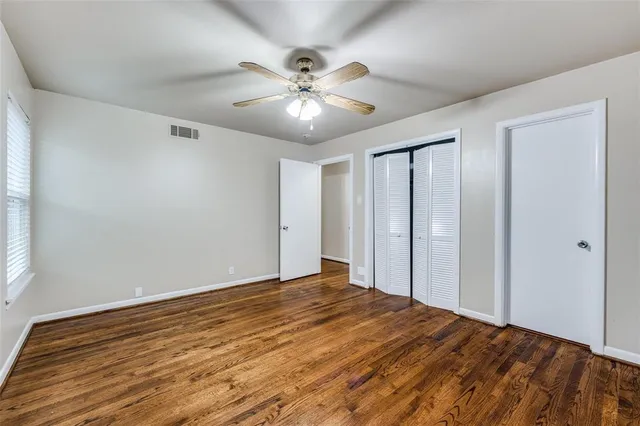a view of empty room with wooden floor and fan