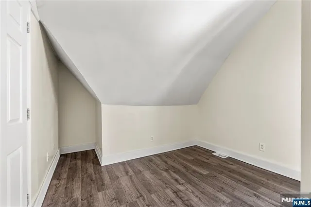 a view of an empty room with wooden floor and closet