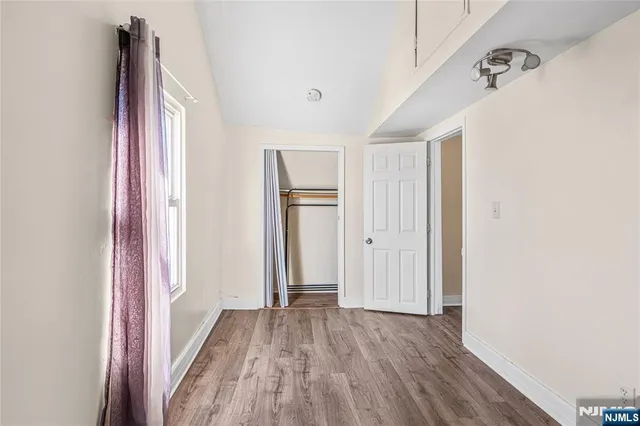 a view of a hallway with wooden floor and closet
