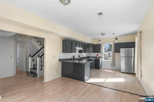 a kitchen with stainless steel appliances kitchen island wooden cabinets and refrigerator