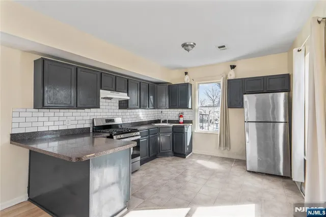 a kitchen with stainless steel appliances granite countertop a stove refrigerator sink and microwave