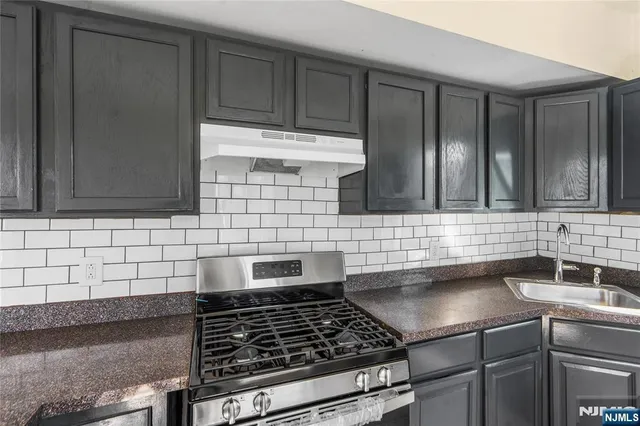 a kitchen with granite countertop a sink stainless steel appliances and cabinets