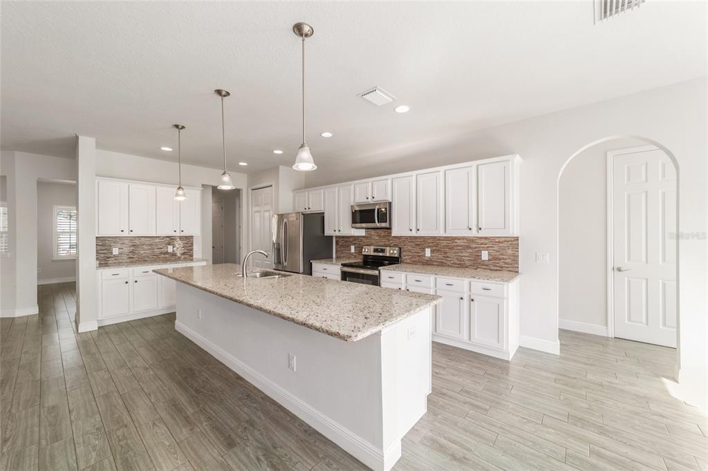 6429 Southwest 45th Avenue Ocala, FL 34474 - Photo 17 of 56 a large white kitchen with kitchen island a sink a center island stainless steel appliances and a cabinets