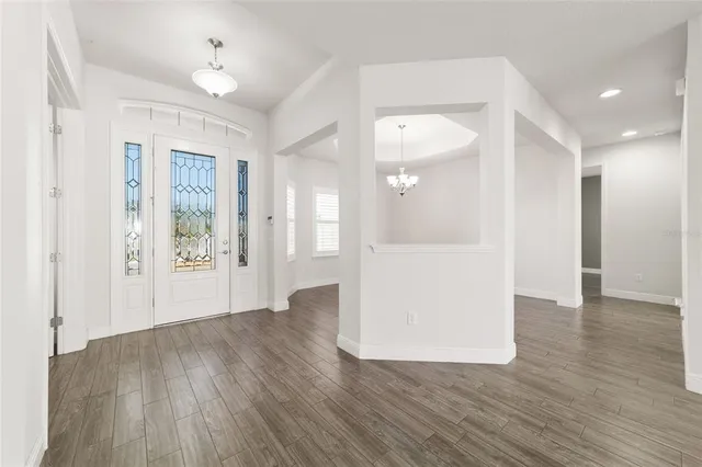 an empty room with wooden floor ceiling fan and windows