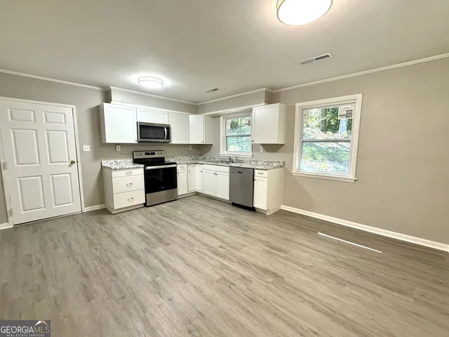 a large kitchen with stainless steel appliances granite countertop a stove top oven a sink dishwasher and wooden floor