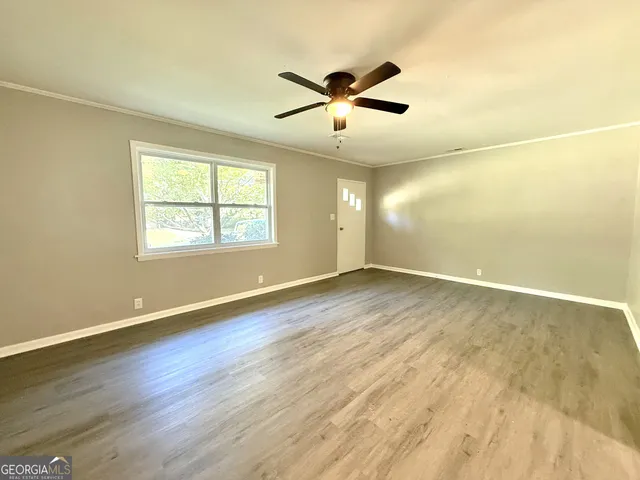 a view of an empty room with wooden floor and a window