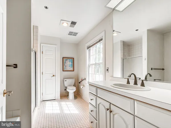 a bathroom with a sink a toilet a large mirror and a window