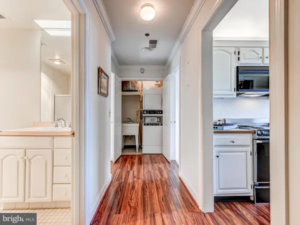 a view of a hallway with wooden floor and cabinets
