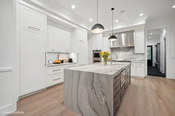 a kitchen with kitchen island stainless steel appliances a sink cabinets and a wooden floor