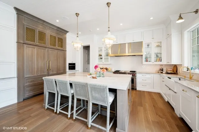 a kitchen with stainless steel appliances kitchen island granite countertop a wooden floor and white cabinets
