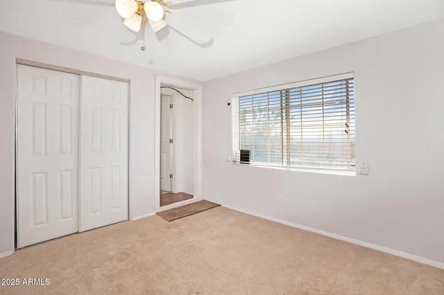 an empty room with a ceiling fan and a window