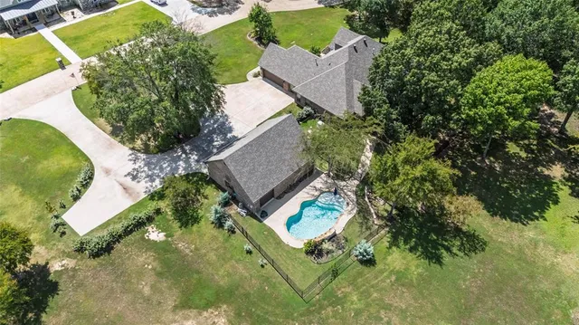 an aerial view of a house with a yard and trees all around
