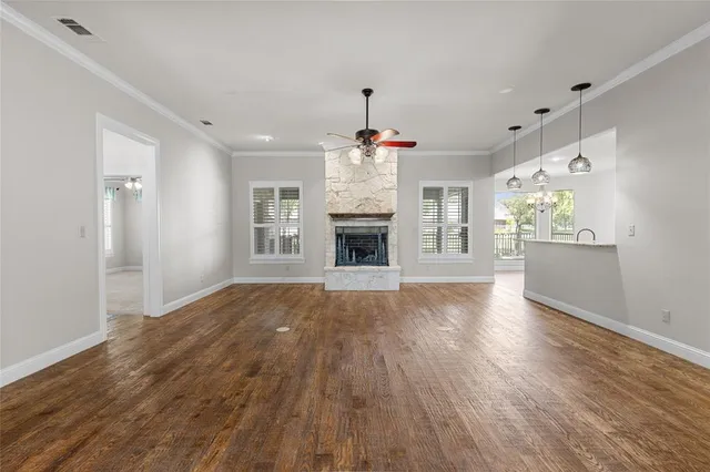 a view of an empty room with wooden floor fireplace and a window