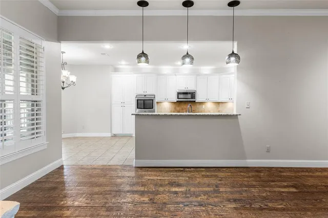 a view of a kitchen with stainless steel appliances granite countertop a sink window and wooden floor