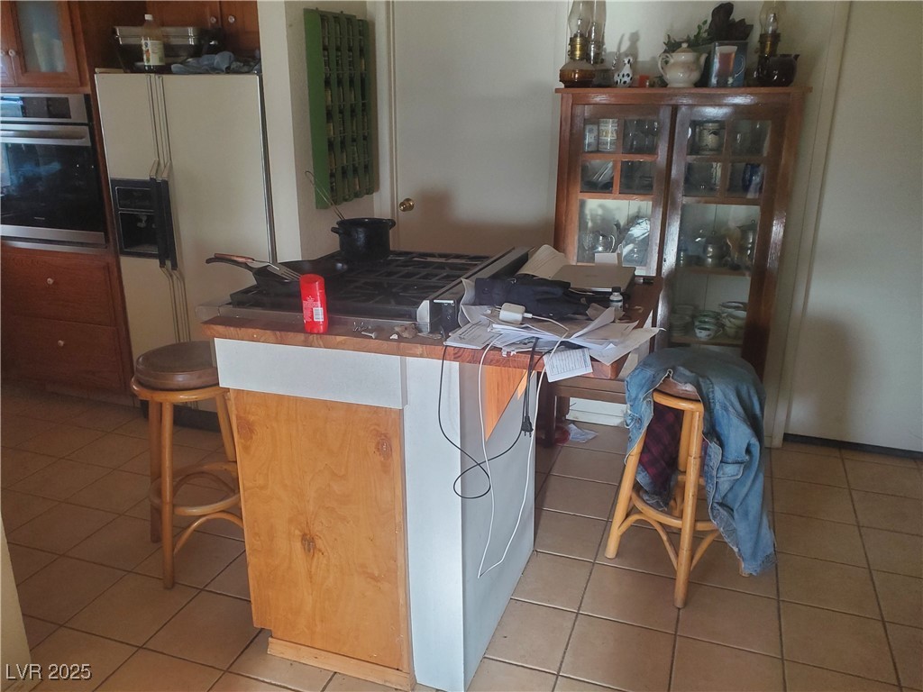 1281 Meadow Lane Pioche, NV 89043 - Photo 13 of 34 Kitchen with oven, a breakfast bar area, and light tile patterned flooring