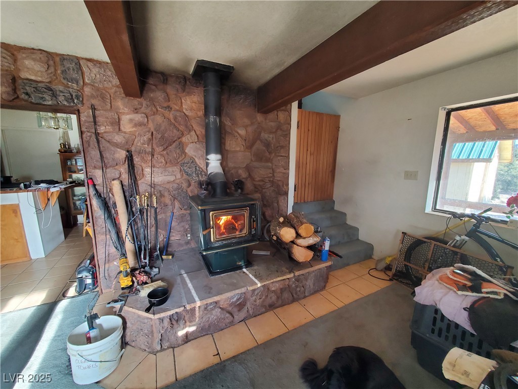 1281 Meadow Lane Pioche, NV 89043 - Photo 2 of 34 Living room featuring beam ceiling, tile patterned floors, and a wood stove