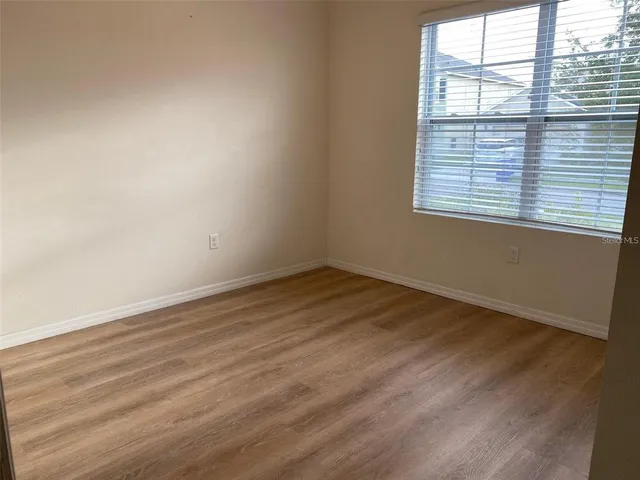 a view of an empty room with wooden floor and closet