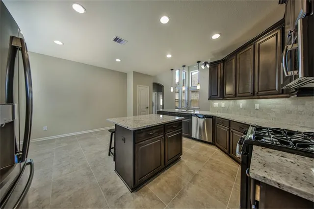 a kitchen with stainless steel appliances granite countertop a stove a sink and a refrigerator with wooden floor