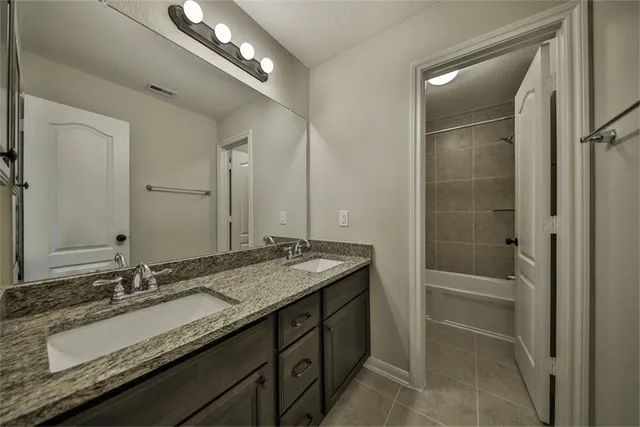 a bathroom with a granite countertop sink double vanity and a mirror