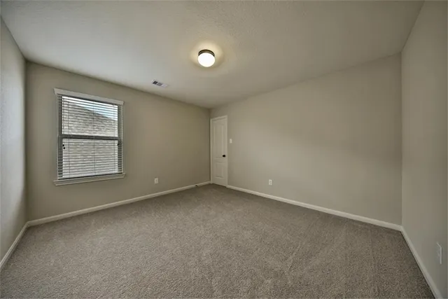 an empty room with ceiling fan and window
