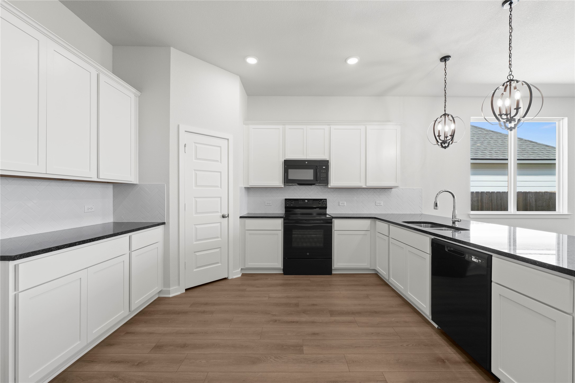 220 Gus Loop Georgetown, TX 78626 - Photo 15 of 18 A contemporary kitchen offers a streamlined U-shaped layout, bright white cabinetry, and rich wood flooring.
