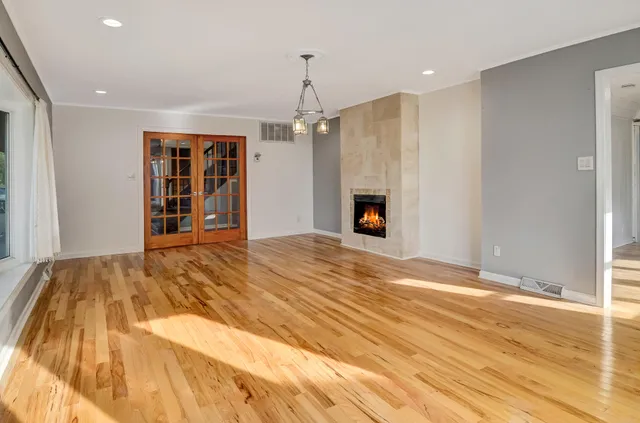a view of an empty room with wooden floor and a kitchen