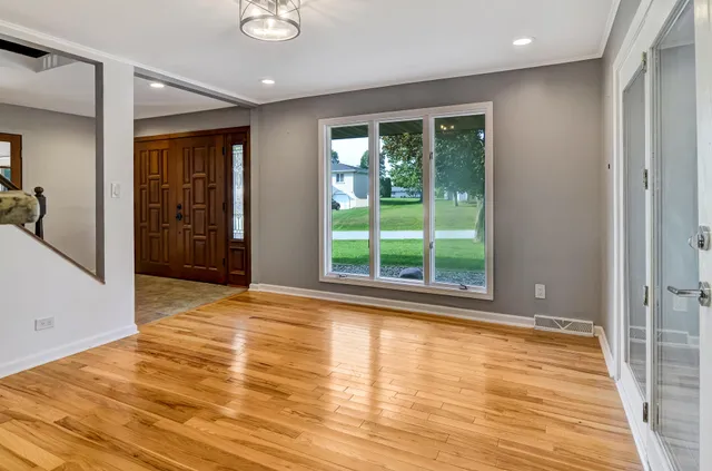 a view of an empty room with wooden floor and a window