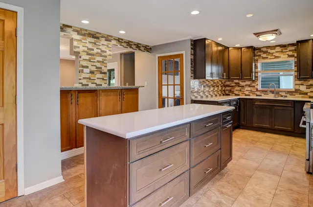 a kitchen with kitchen island granite countertop a stove and a sink