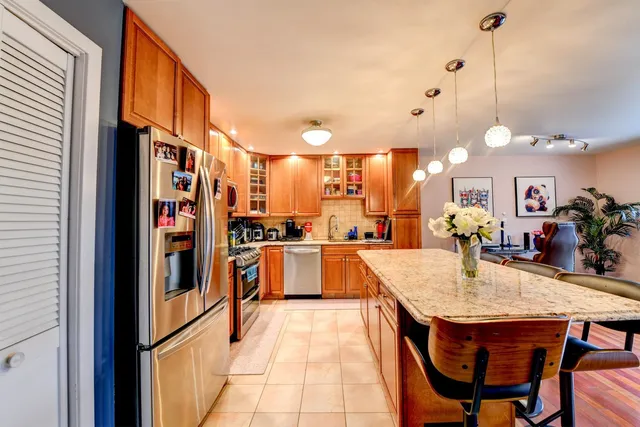 a kitchen with stainless steel appliances granite countertop table chairs and a refrigerator