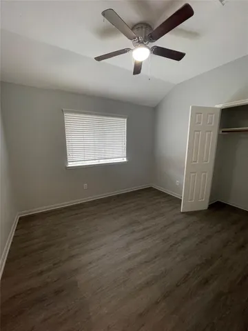an empty room with wooden floor chandelier fan and windows
