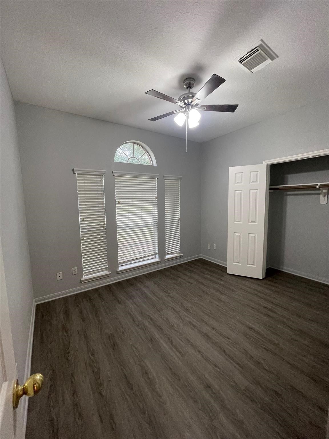 3310 North Mason Road Katy, TX 77449 - Photo 13 of 14 an empty room with wooden floor chandelier fan and windows