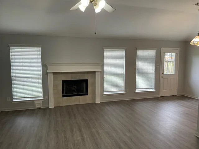 an empty room with wooden floor fireplace and windows