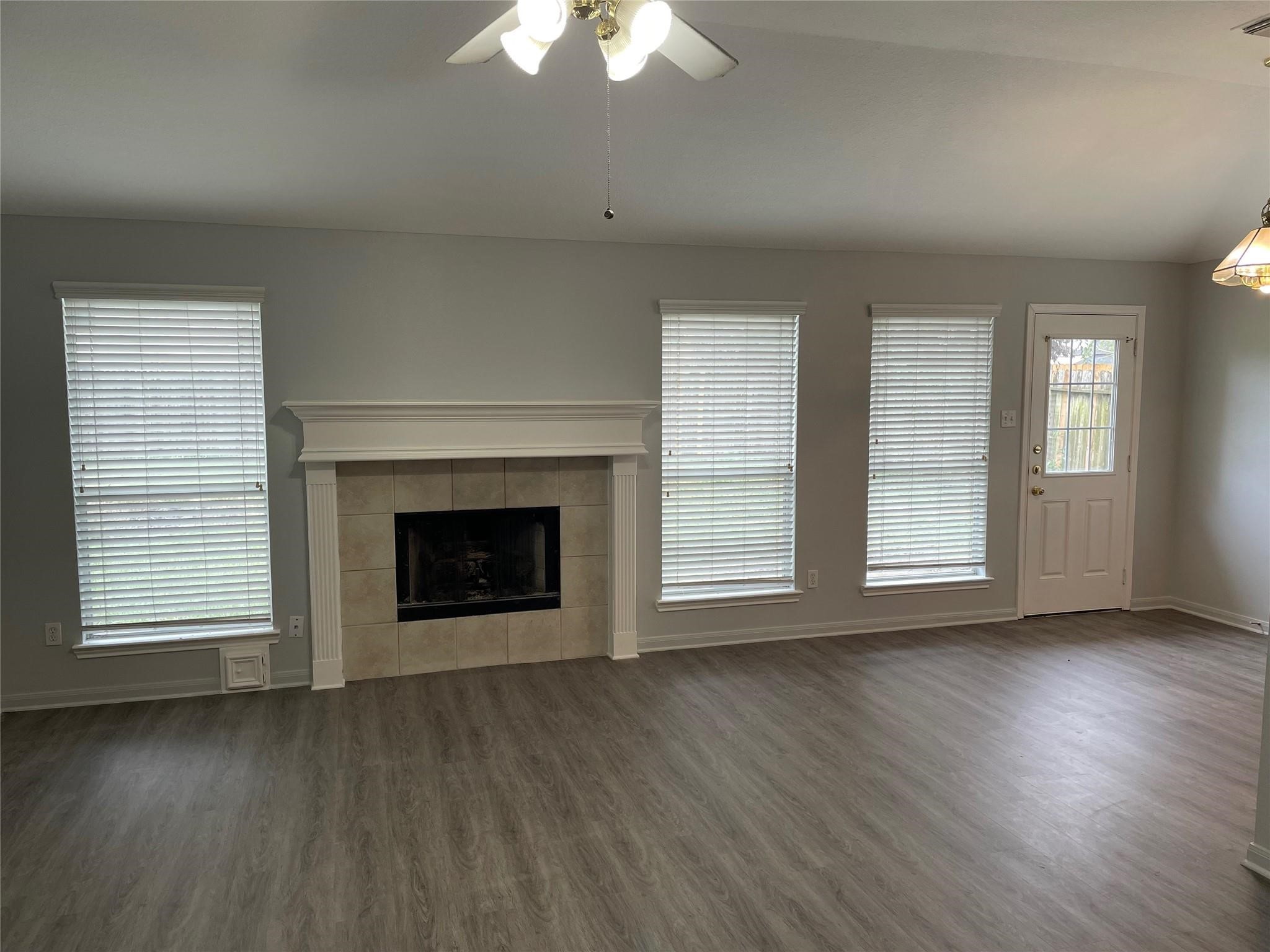 3310 North Mason Road Katy, TX 77449 - Photo 5 of 14 an empty room with wooden floor fireplace and windows