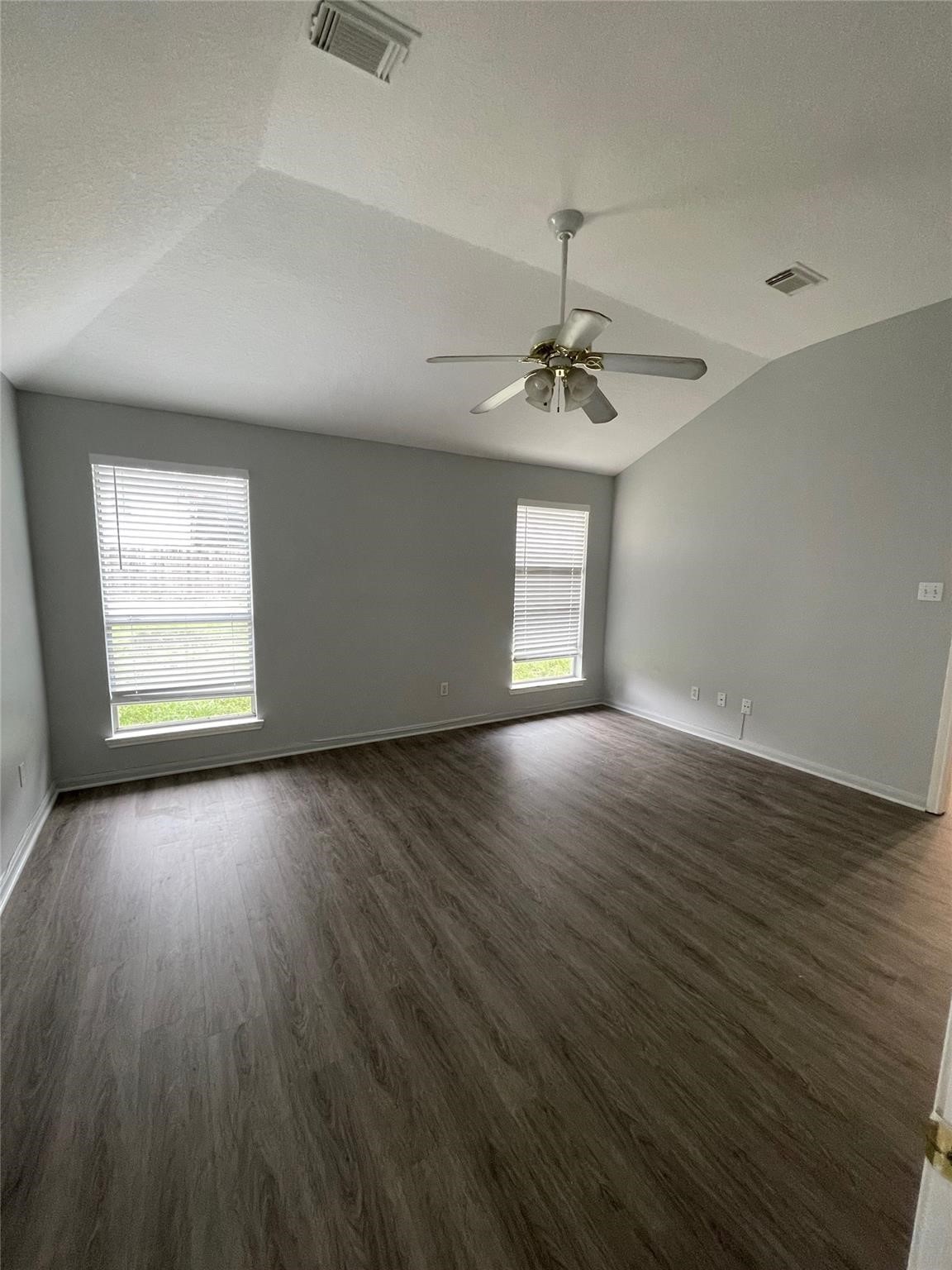 3310 North Mason Road Katy, TX 77449 - Photo 9 of 14 an empty room with wooden floor chandelier fan and windows