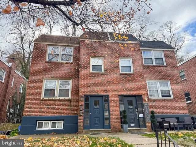 a front view of a building with garden and trees