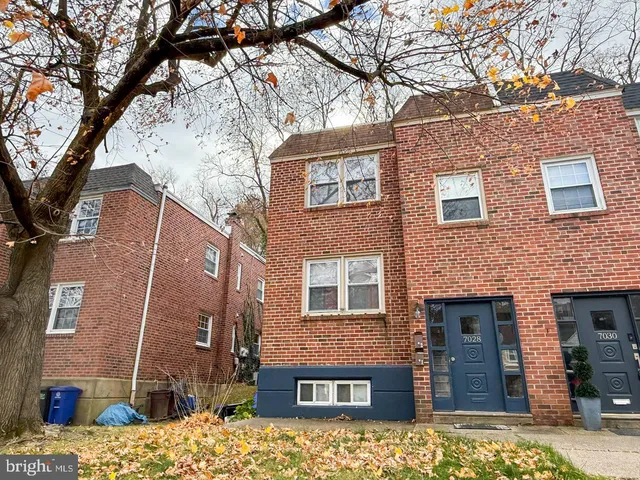 a brick building that has a tree in front of the house