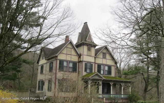 a view of a white house next to a large tree