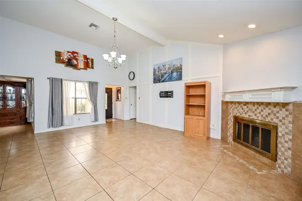 a view of an empty room with window and kitchen view