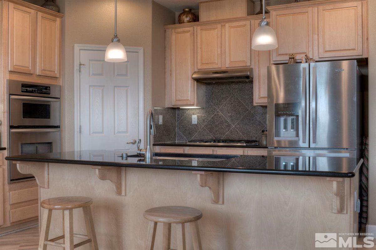 425 Manciano Way Reno, NV 89521 - Photo 6 of 28 a kitchen with stainless steel appliances granite countertop a refrigerator a stove and a sink with wooden cabinets