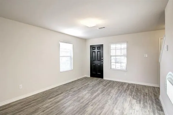 a view of an empty room with a window and wooden floor