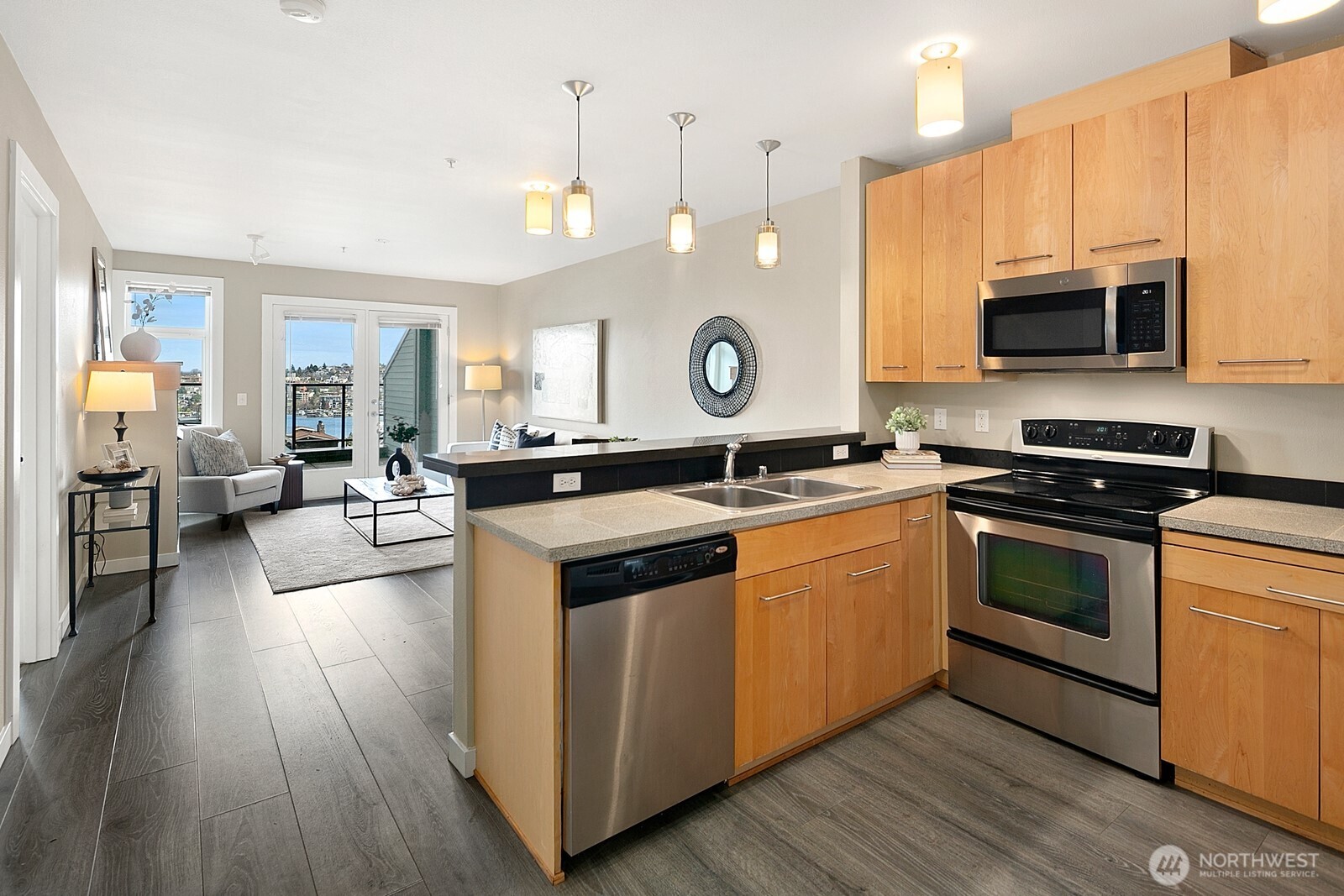655 Crockett Street, Unit A204 Seattle, WA 98109 - Photo 10 of 23 a large kitchen with stainless steel appliances granite countertop a stove a sink dishwasher a microwave oven and a dining table with wooden floor