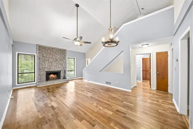 a view of a livingroom with a fireplace a ceiling fan and windows