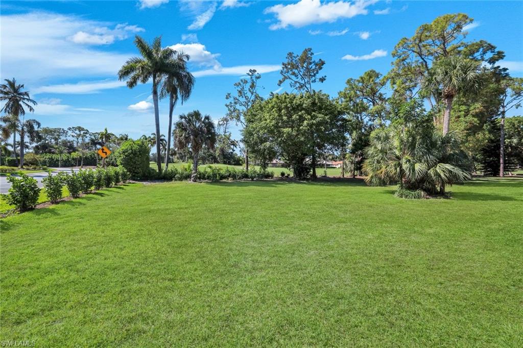 5857 Rattlesnake Hammock Road, Unit 101 Naples, FL 34113 - Photo 17 of 19 Expansive green lawn with established landscaping and mature palm trees