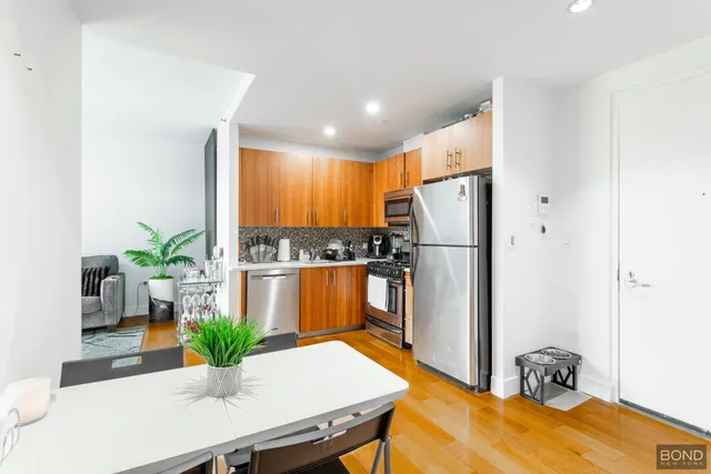 a kitchen with stainless steel appliances a white table and chairs in it