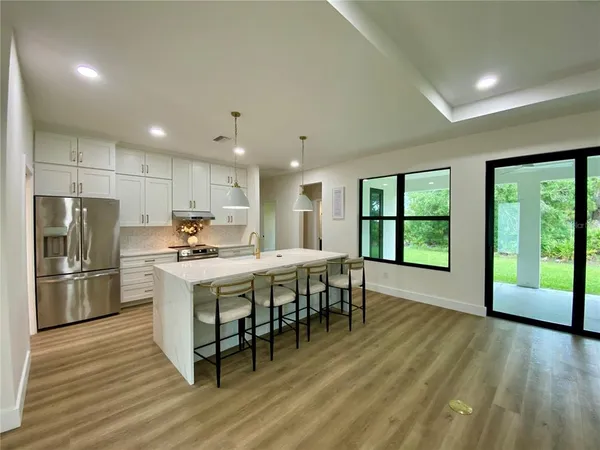 a kitchen with stainless steel appliances granite countertop a stove a refrigerator a sink a dining table and chairs with wooden floor