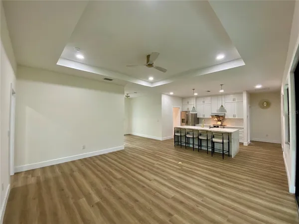 a view of kitchen with kitchen island a sink wooden floor and a refrigerator
