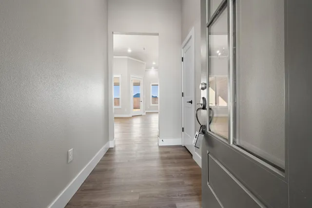 a view of a hallway with wooden floor and a bathroom