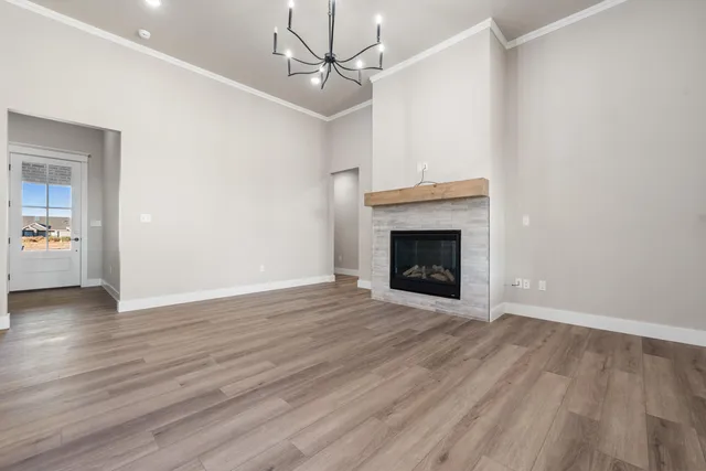 a view of an empty room with wooden floor fireplace and a window